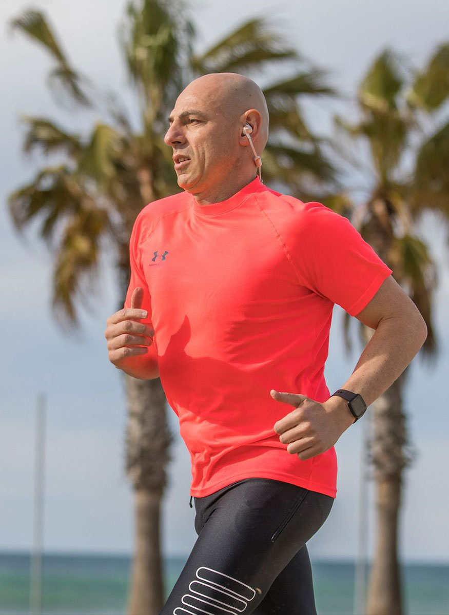 El entrenador corre afuera, con palmeras y el océano al fondo.